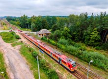 Widok z powietrza na przystanek kolejowy Ełk Szyba Wschód. Na przystanku widoczny pociąg. W oddali przejazd kolejowo-drogowy.