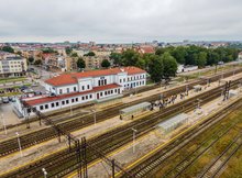 Widok z powietrza na budynek dworca i perony na stacji w Ełku. Widać pasażerów oczekujących na pociąg.