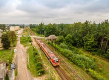 Widok z powietrza na przystanek kolejowy Ełk Szyba Wschód. Na przystanku widoczny pociąg. W oddali przejazd kolejowo-drogowy.