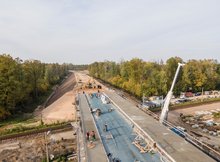 Widok z powietrza na budowę wiaduktu drogowego w Szepietowie nad trasą Rail Baltica. Widać maszyny budowlane i pracujących robotników.