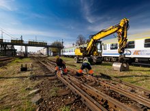 Widoczne są prace rozbiórkowe na stacji kolejowej w Białymstoku. W tle widoczna kładka dla pasażerów nad torami, pociąg i koparka.