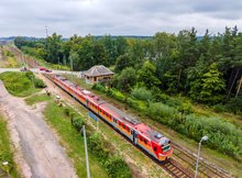 Widok z powietrza na przystanek kolejowy Ełk Szyba Wschód. Na przystanku widoczny pociąg. W oddali przejazd kolejowo-drogowy.